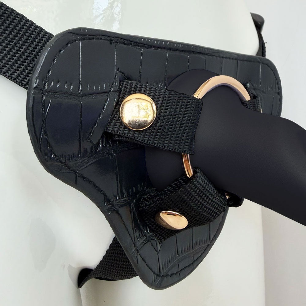 Nexus Fun and Love harness kit with adjustable black strap on harness and black tease silicone dildo, with dildo inserted into the harness zoomed into the base of the Tease in the gold included oring