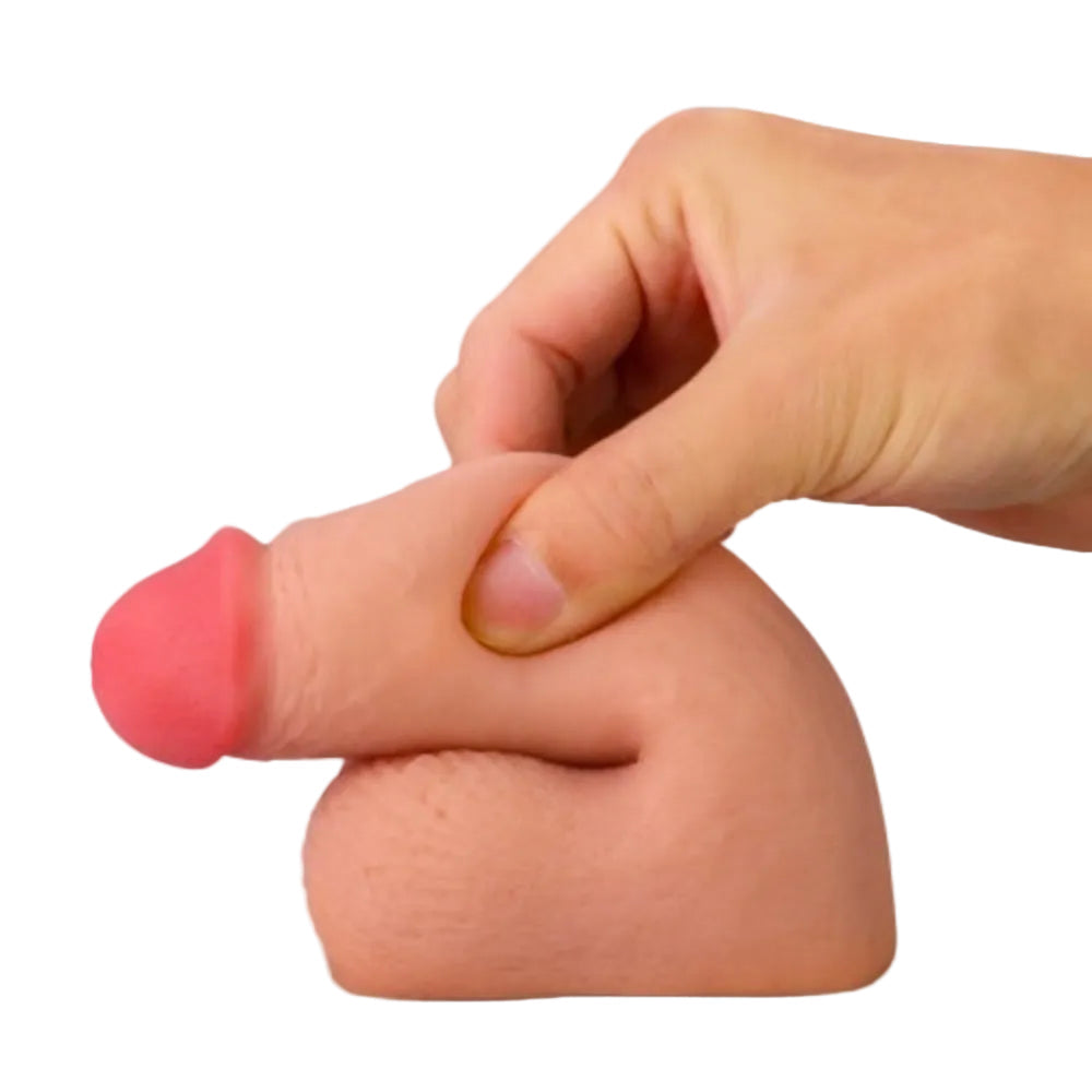 Love toy 5 inch dual layer TPE packing penis form the side in a flaccid position, with the shft being pinched to show softness